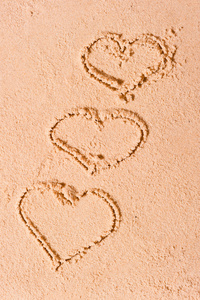 在潮湿的沙滩上绘制的三颗心图片