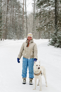 上一次降雪在树林里散步的狗的女人