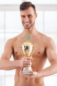 肌肉发达的男人抱着金灿灿的奖杯