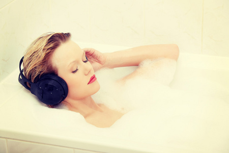 漂亮的女人和耳机在浴