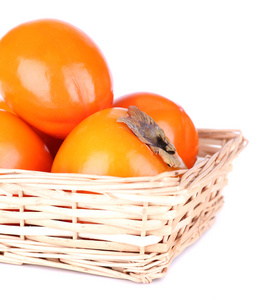 在孤立的白色衬底上的柳条篮子里的熟柿子