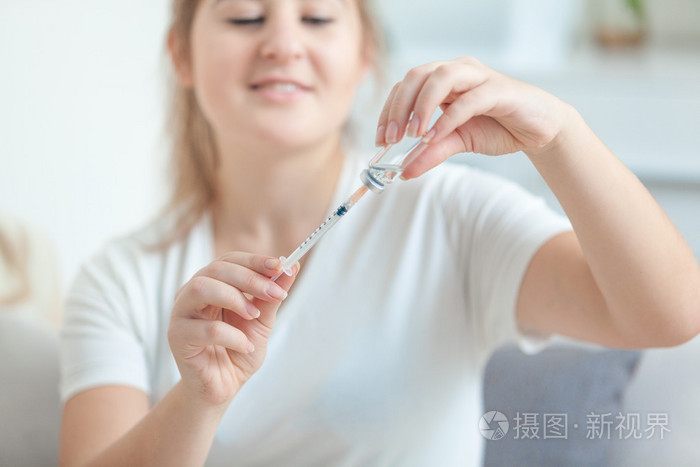 年轻女子灌装注射器从安瓿的肖像