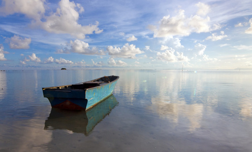 寂寞的小船在海上用反射的蓝蓝的天空照片