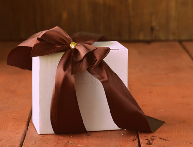在一个木制的背景上的缎带蝴蝶结白色礼品盒