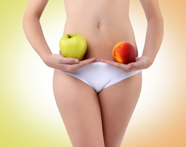 拿着苹果和桃子用手在肚子里附近的女人