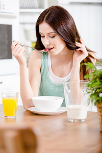 女孩吃美味的谷类食物和橙汁