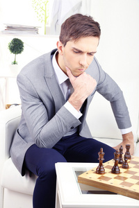 优雅的年轻商人坐在沙发上和在家里下棋