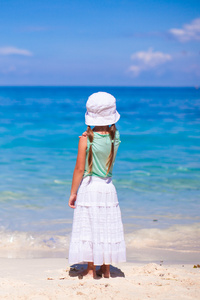 在异国风情的海滩上后视图的可爱的小女孩