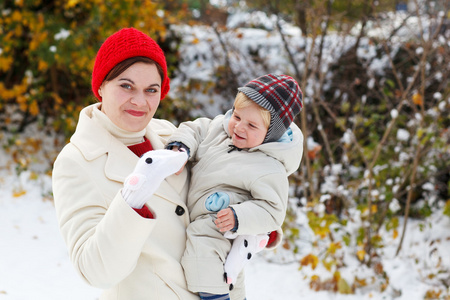 母亲和蹒跚学步的孩子冬天天过与雪的乐趣