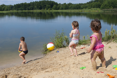 年幼的孩子在湖边的沙滩上玩