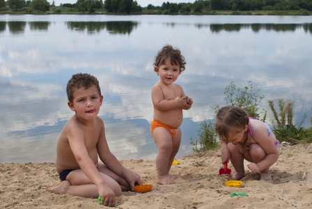 年幼的孩子在湖边的沙滩上玩
