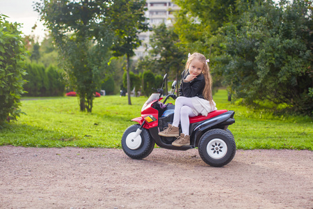漂亮的小女孩，对她的玩具自行车绿色公园玩乐