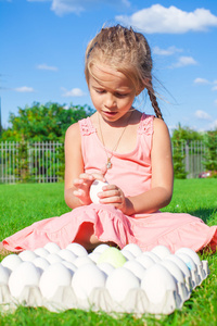 肖像的可爱的小女孩玩白色的复活节蛋在绿色草地上