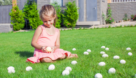 和白色的复活节彩蛋在院子里玩的小可爱女孩