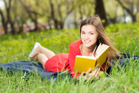 年轻漂亮的女孩在公园里看书