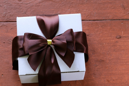 在一个木制的背景上的缎带蝴蝶结白色礼品盒