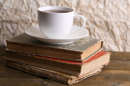 喝杯热茶对纸张背景上的桌子上的书
