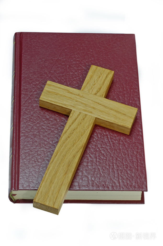 木制十字架躺在一本旧的红色皮革圣经上. 孤立的