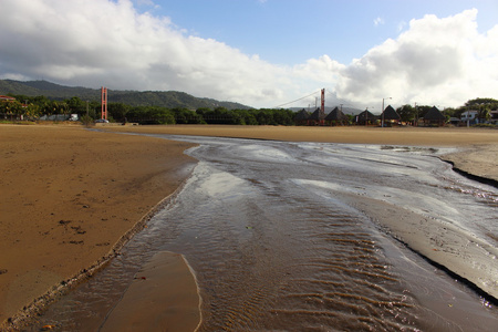 河与悬索桥在望的海滩上图片