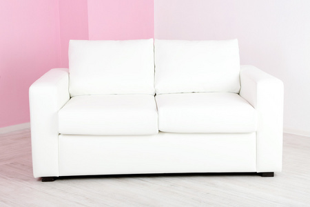 在房间里粉红色墙背景上的白色沙发