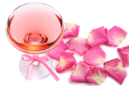 有玻璃和孤立在白色的玫瑰花瓣粉红色酒的组成