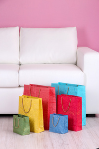 在沙发上，对颜色的背景墙上的彩色购物袋。