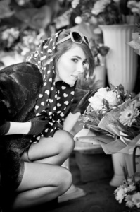 美丽的黑发女人，戴着手套选择在花店的鲜花。用太阳镜和头围巾在花店里的时尚女性。选择鲜花   城市拍摄的黑衣美女