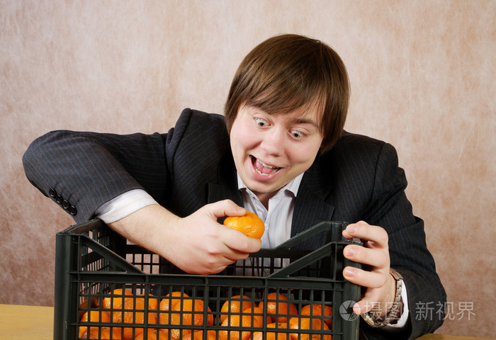 那个年轻人从框中快乐地吃橘子