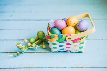 在蓝色木背景上的篮子中的复活节彩蛋