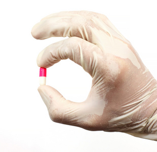 在白色背景上的医用手套的粉红色和白色胶囊