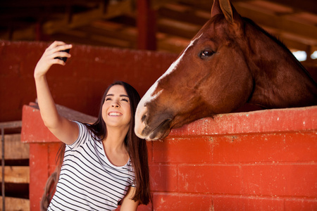 拍照的她和她的马在马厩里的女人