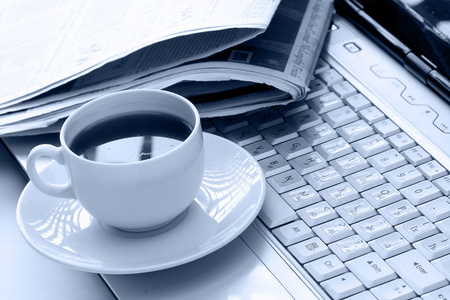 杯咖啡和一份报纸在笔记本电脑上