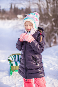 小可爱的快乐的女孩在阳光明媚的冬日雪