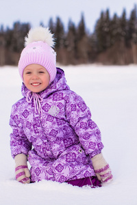 快乐可爱的小姑娘坐在雪地上，在冬天阳光明媚的日子