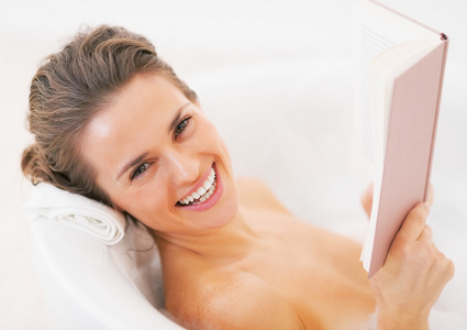 微笑在浴缸里的年轻女子看书