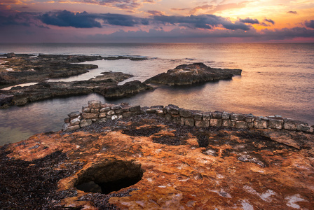 海和岩石海岸，与古代遗址上空的日落