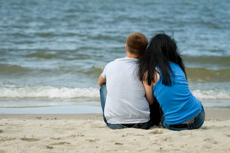 爱对年轻夫妇正坐在海边