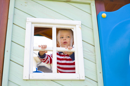 四岁的男孩寻找在窗口中的儿童