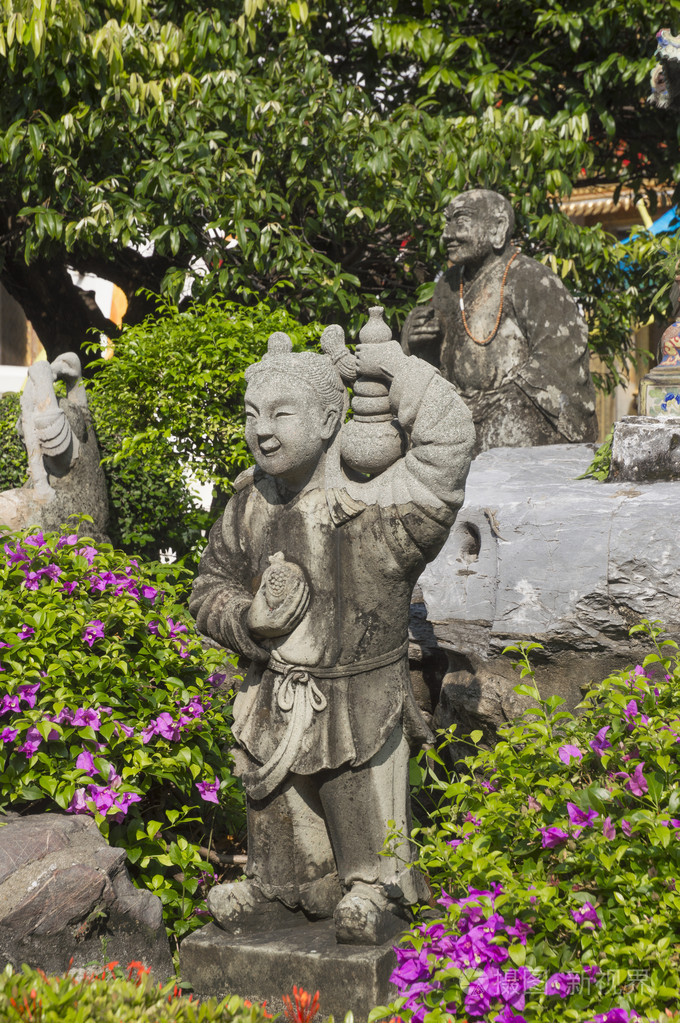 中国小女孩和一个和尚在绿色的花园里的雕像