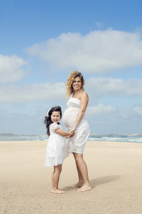 怀孕的妇女和她的女儿在海滩上