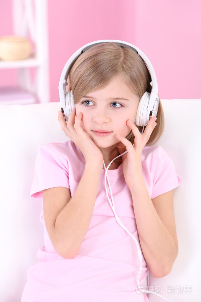 小女孩坐在沙发上,听音乐在房间里