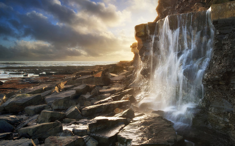 美丽的风景图像瀑布流入在海滩上的岩石