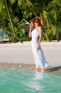 美丽的女人，在热带的海滩上沿着海边散步