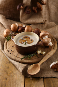 在锅中，新鲜和干蘑菇，木制的桌子，麻布背景上的蘑菇汤的组成