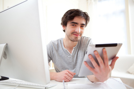 年轻的放松的男人在办公室使用平板电脑的肖像
