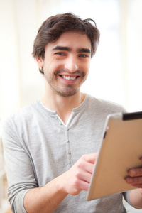 年轻的男人微笑着用一台平板电脑