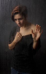 在湿的玻璃后面的女孩