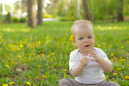年轻可爱的性格开朗宝宝坐在绿色的草地上玩耍的公园