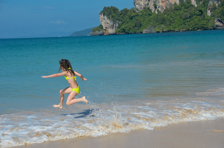 快乐的女孩在海面上的热带海滩玩