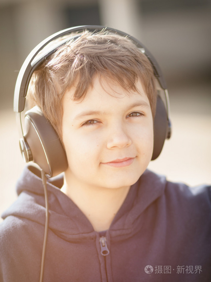 小男孩戴着耳机在葡萄酒看起来